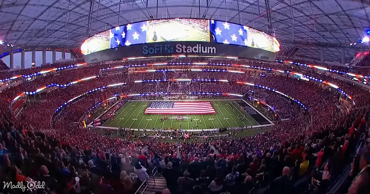A packed SoFi Stadium with a large American flag on the field and a crowd cheering.