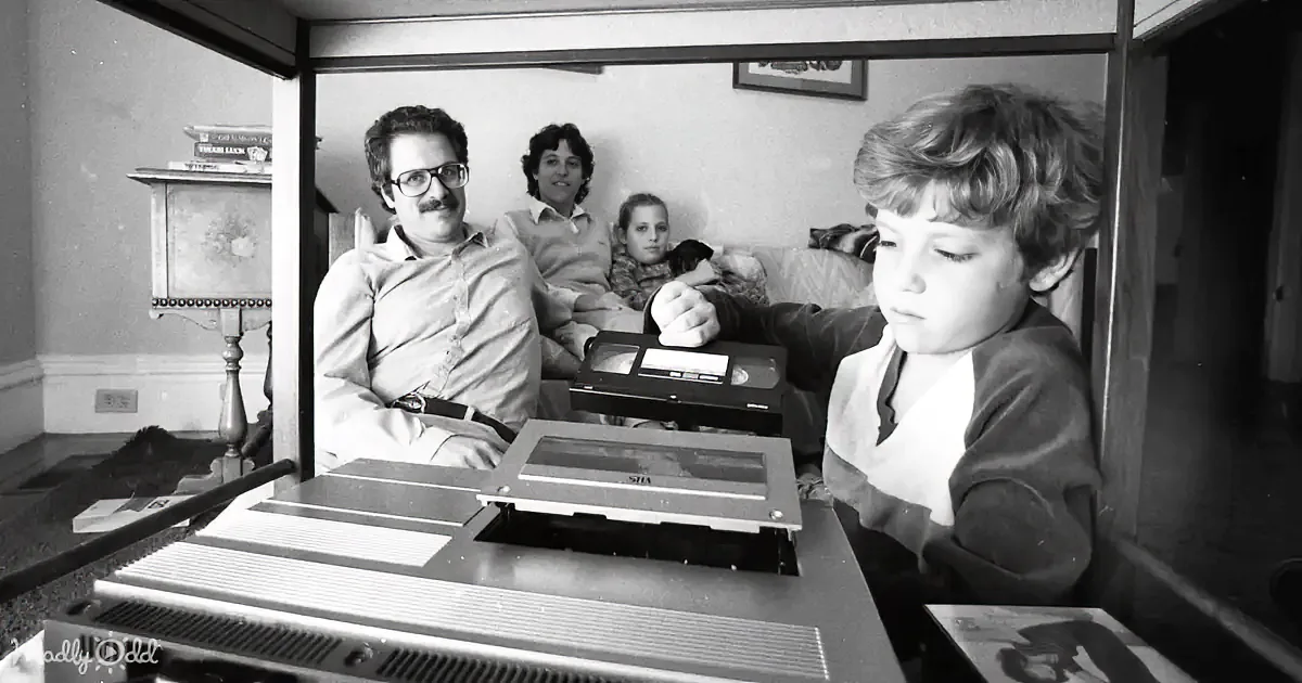 A young boy is focused on assembling a model, while a woman in a red outfit smiles in a vintage setting.