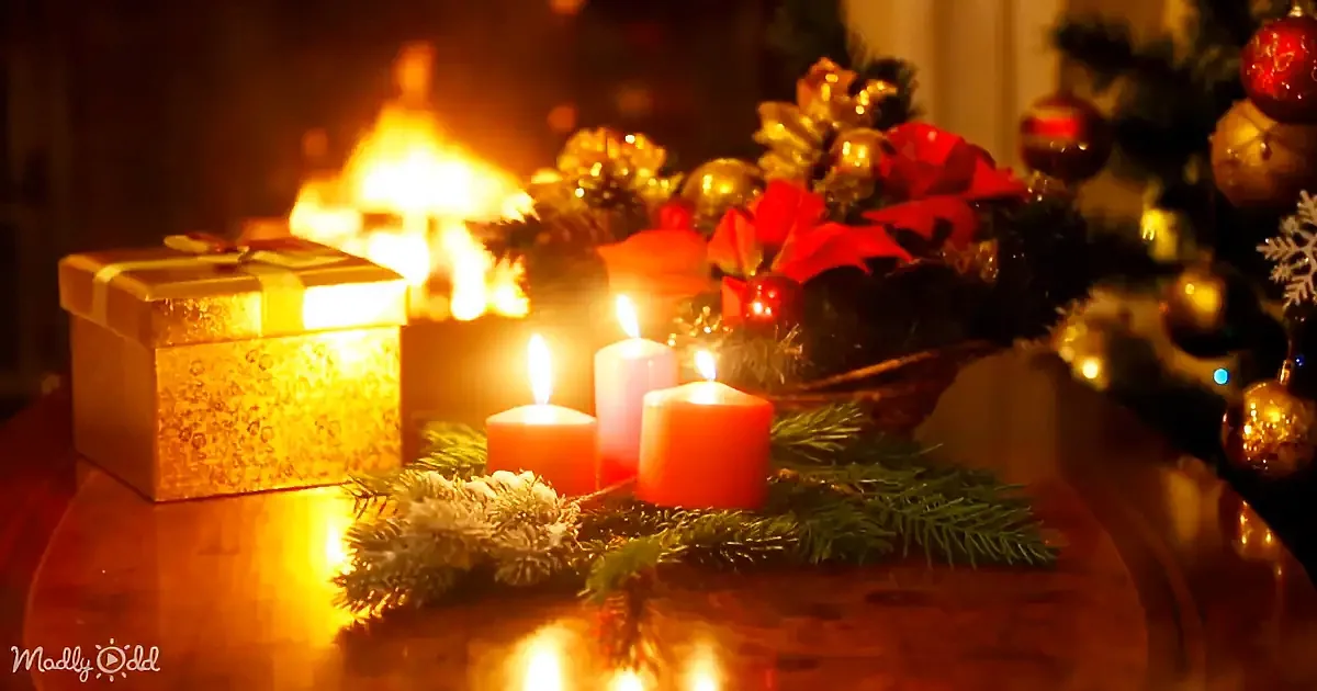 A festive Christmas scene with candles, pine branches, ornaments, and a gift box illuminated by a warm fireplace glow.