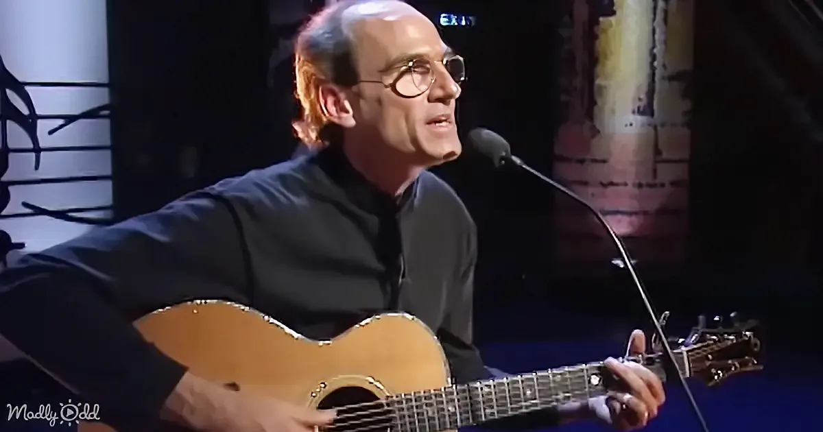 A man with glasses and a black shirt speaks into a microphone in front of a "Words & Music" backdrop.