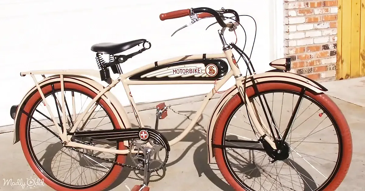 A vintage-style bicycle with red tires and "Motorbike" branding is parked on a concrete surface.