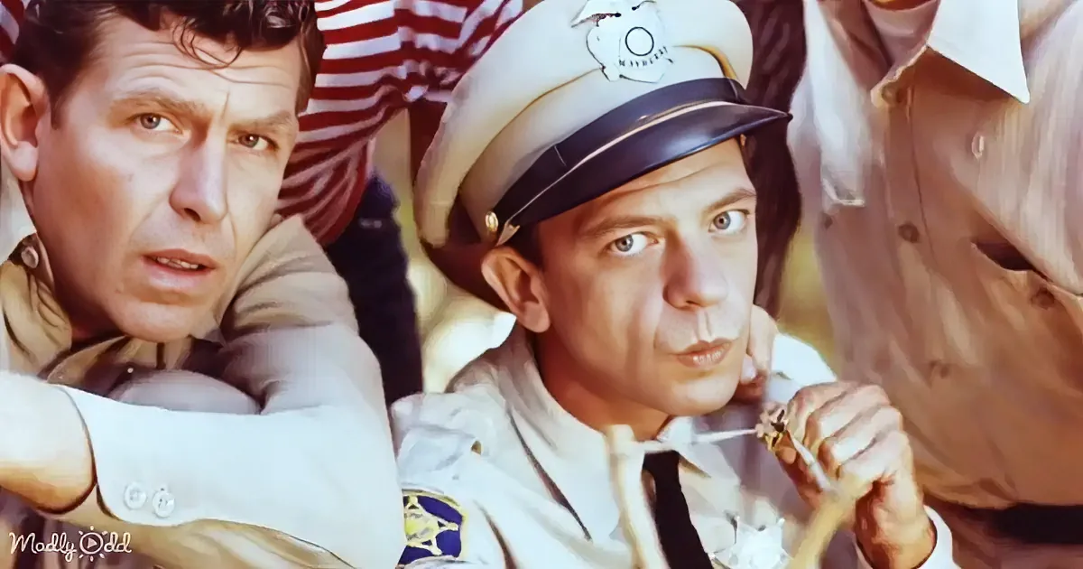 A man in a police uniform is holding a toothpick, looking concerned, with another man in a tan shirt beside him.