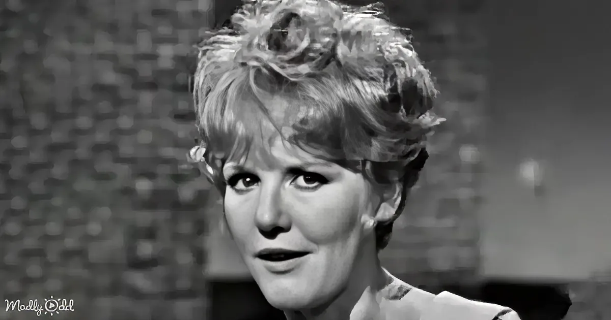 A woman with short, curly hair and a serious expression is shown in a black-and-white image.