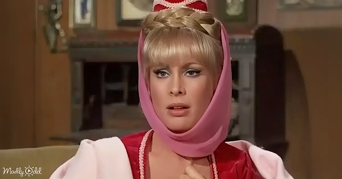 A person in a pink and red costume with a head covering is seated, looking slightly to the side.