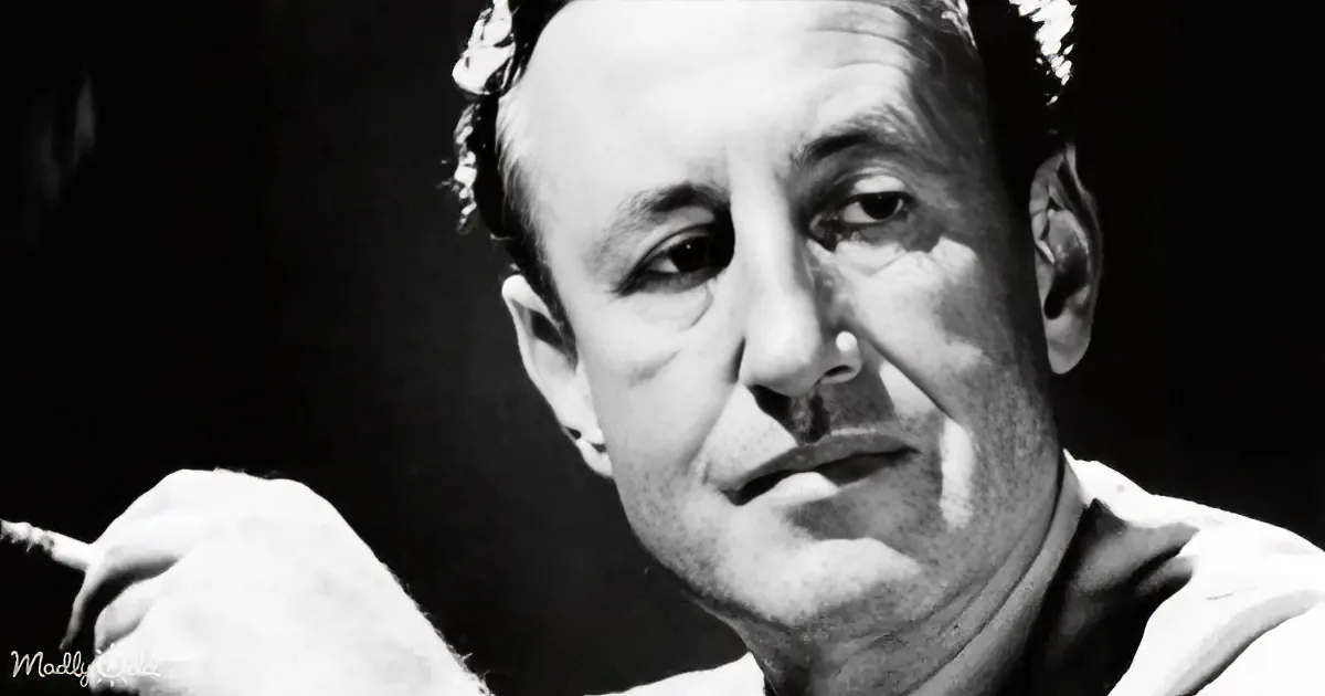 A man with a cigarette, wearing a white shirt, in a black-and-white portrait.