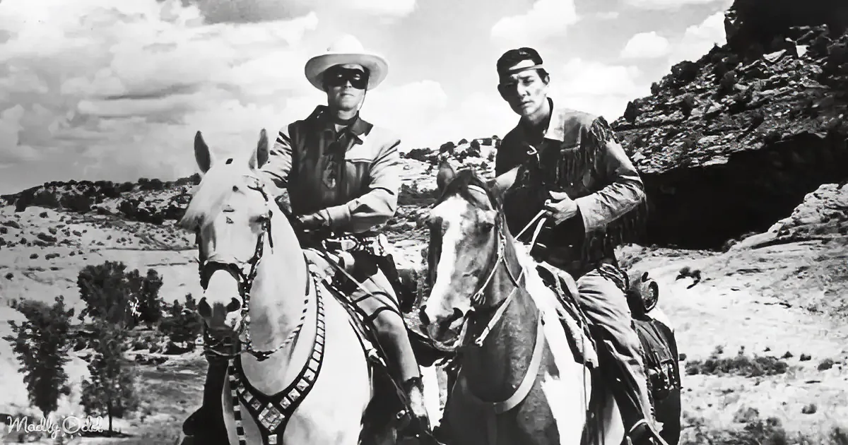 Two cowboys on horses in a rugged landscape, one wearing a mask.