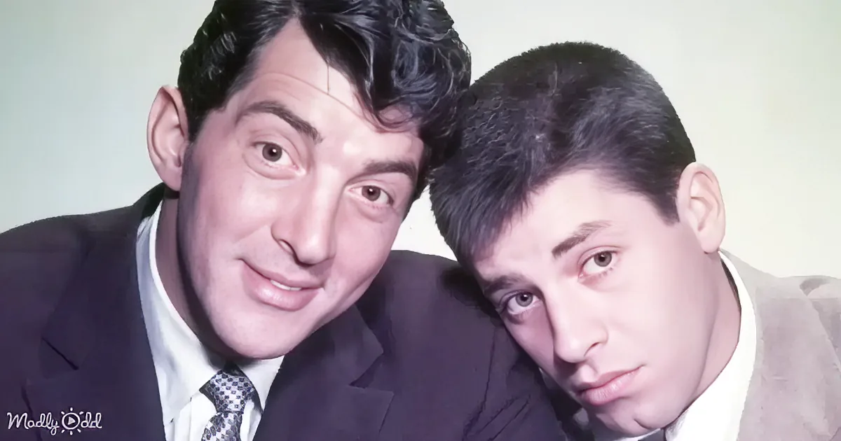 Two men in suits, one smiling, one serious, posing closely together.