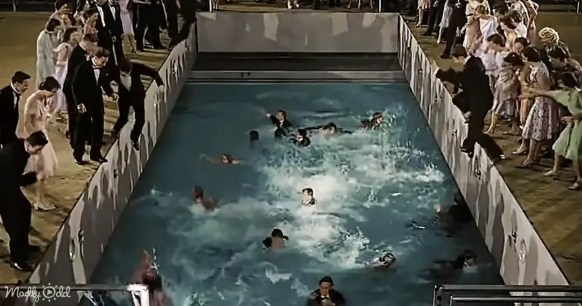 Swimmers in a pool, surrounded by spectators in formal attire, creating a lively scene.