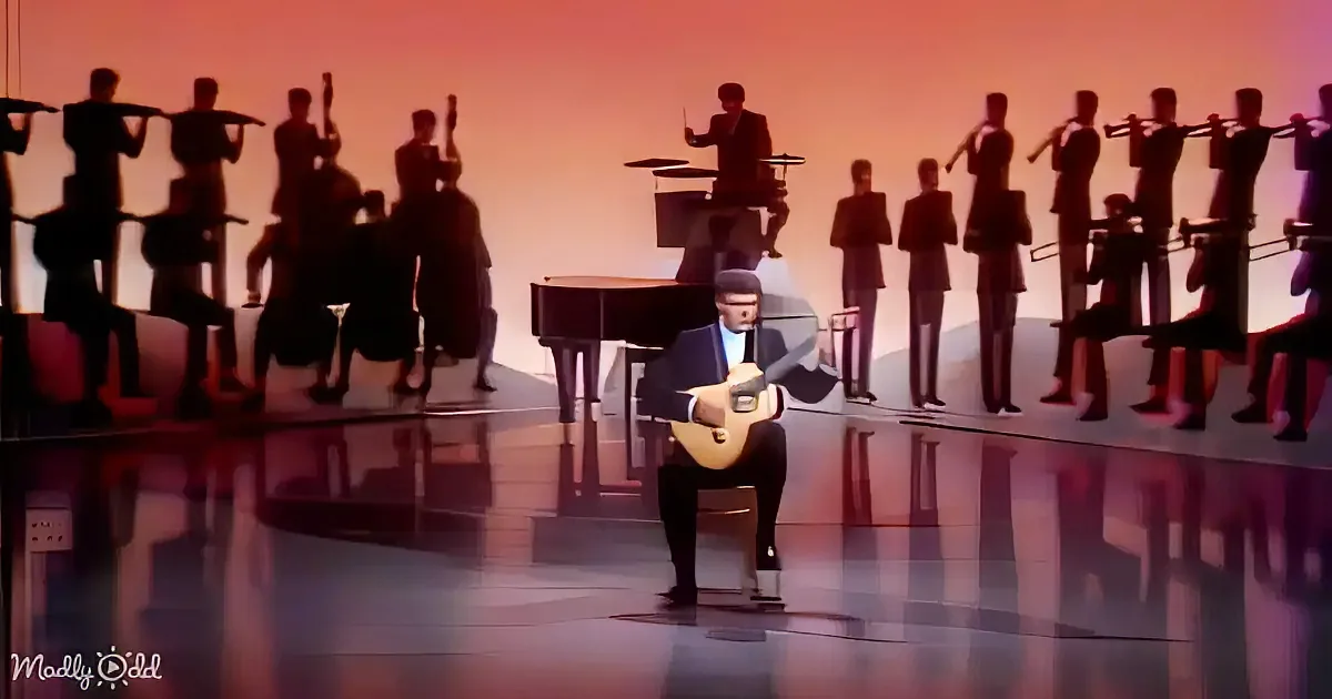 A man in a suit plays guitar on stage with a band in silhouette behind him.
