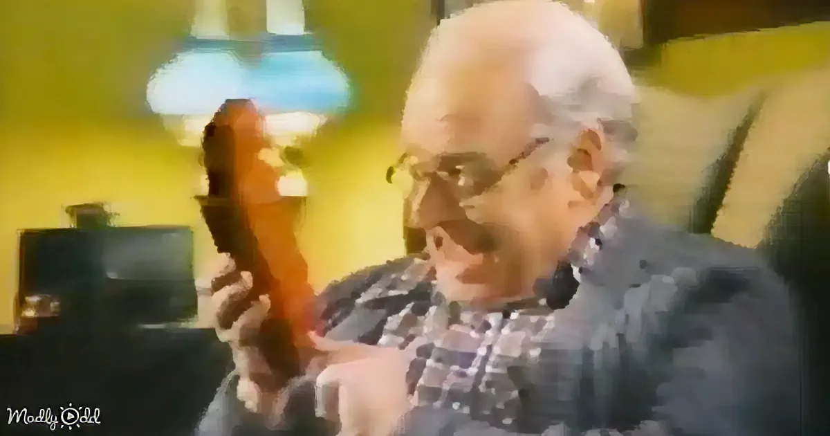 An elderly man with glasses holds a guitar, appearing to play or examine it in a warmly lit room.