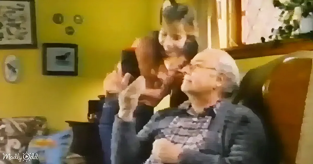A young girl hugs an older man on a couch in a yellow-walled room.
