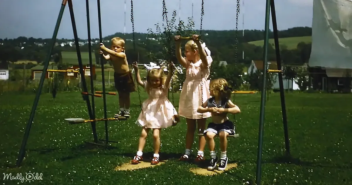 Children playing on swings in a grassy yard with a scenic background.