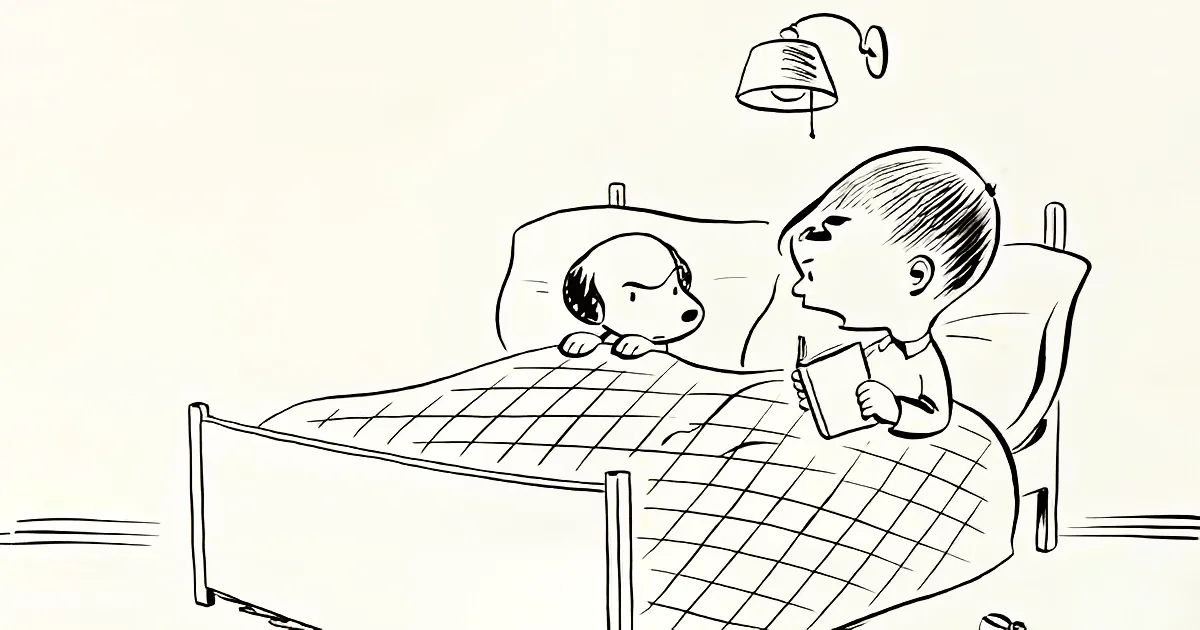 A boy reads a book in bed, while a dog looks on attentively under a lamp.
