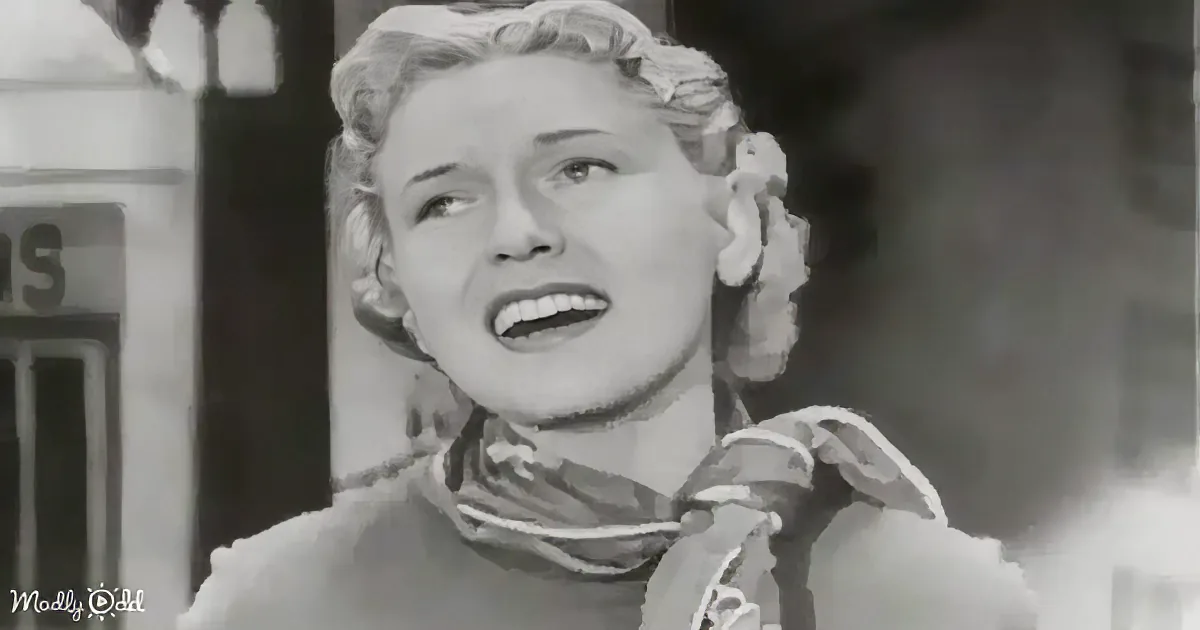 A woman with curly hair and a scarf, possibly singing or speaking, in a black-and-white scene.