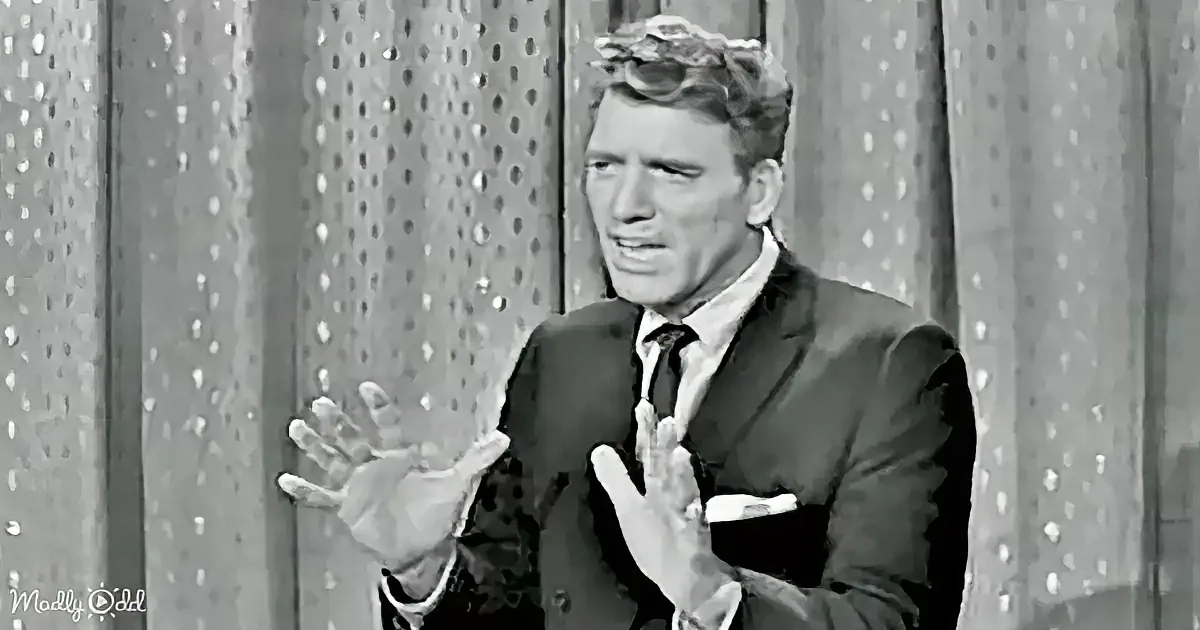 A man in a suit and tie stands in front of a textured wall, looking slightly to the side.