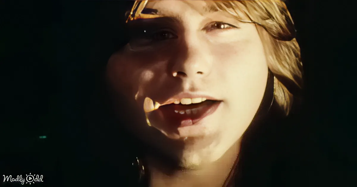 A person with blonde hair and a light source casting shadows on their face, smiling.