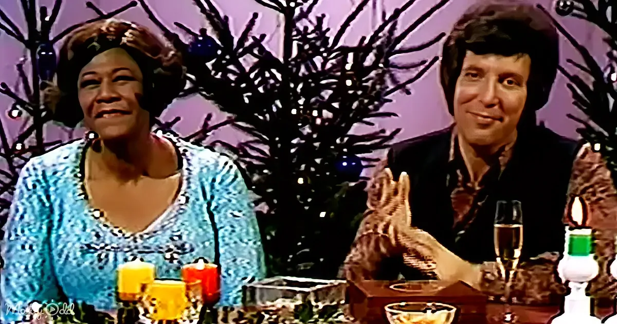 A woman in a blue dress and a man in a black suit sit at a table with candles and a glass of champagne, surrounded by...
