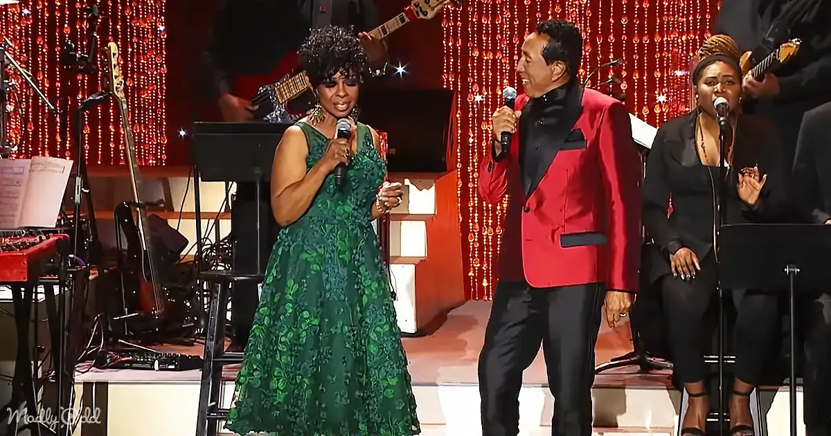 A woman in a green dress sings into a microphone, accompanied by a man in a red suit and another woman in black.
