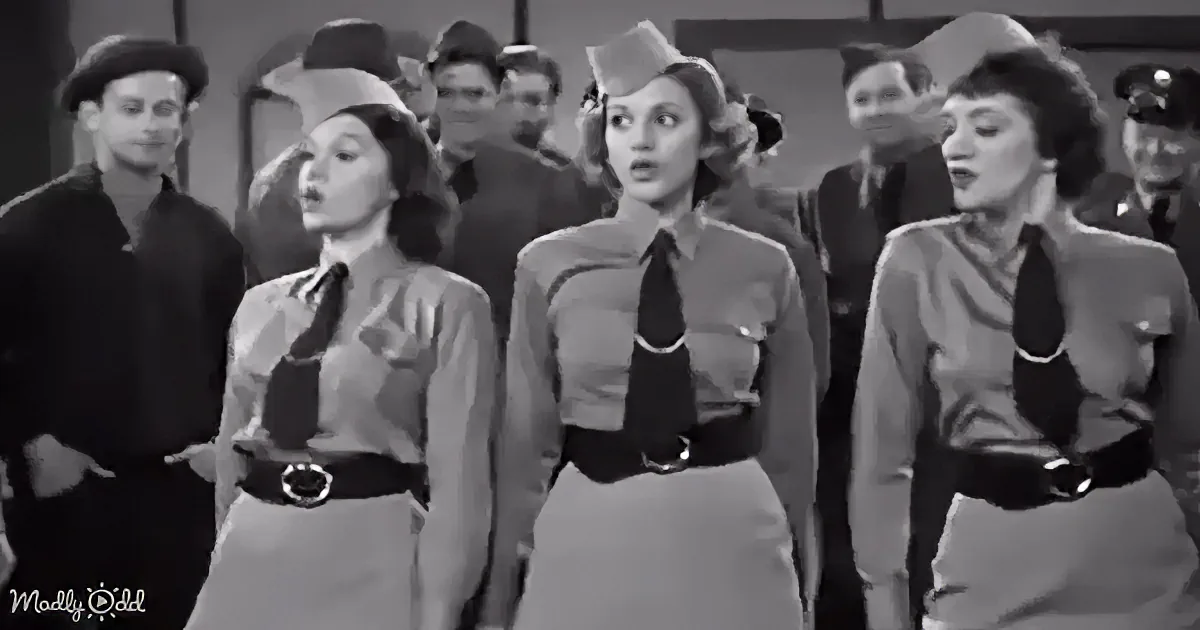 Three women in uniform with belts and ties stand side by side, looking up, while a group of men in various hats and...