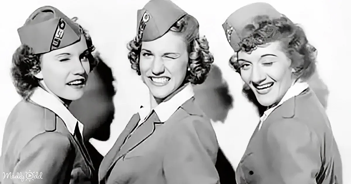 Three women in uniform hats and jackets, smiling and posing together.