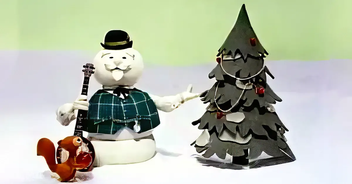A snowman in a kilt plays a banjo next to a decorated Christmas tree.