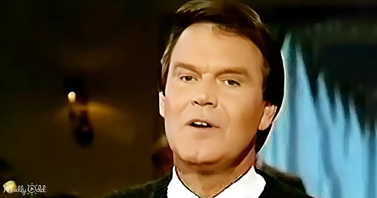 A man in a suit and tie is speaking, with a blurred background and a watermark in the corner.