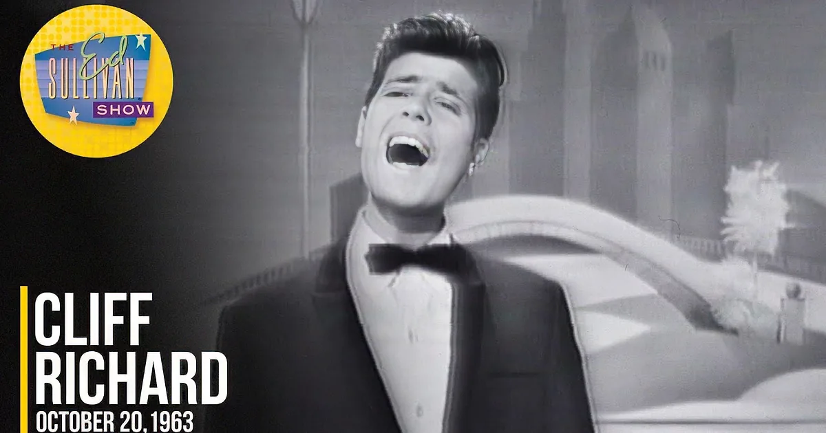 A man with a 1950s hairstyle and suit, mouth slightly open, in a black-and-white image.