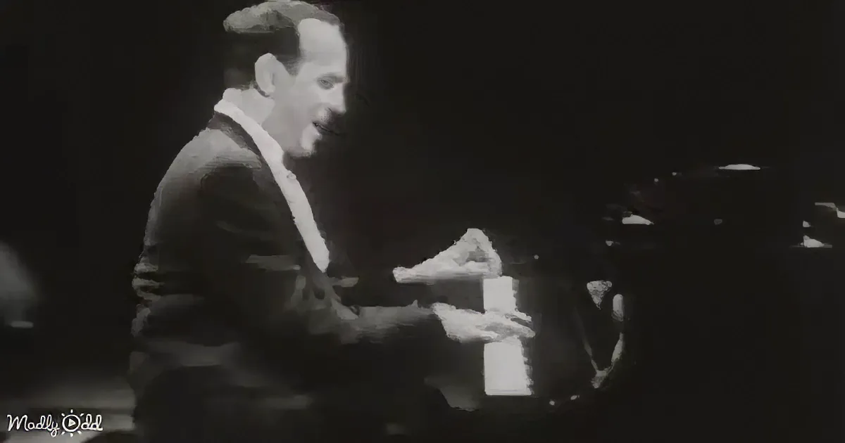 A man in a suit is playing a piano, his hands on the keys, in a dimly lit setting.