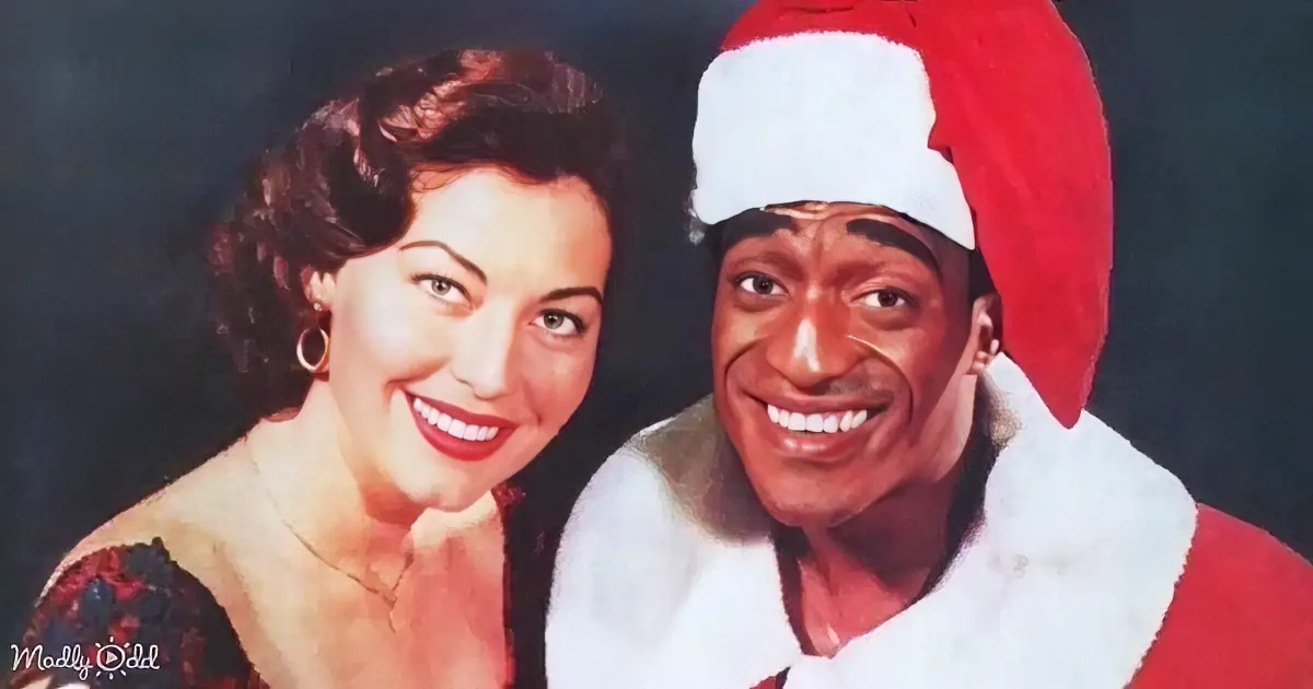 A woman in a red dress smiles next to a man in a Santa hat, both looking happy.