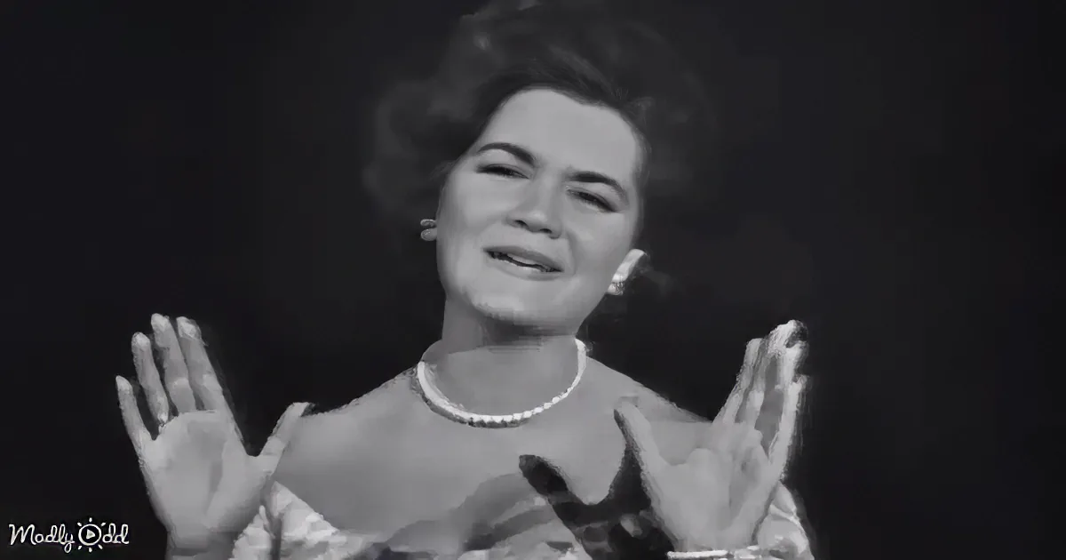 A woman in a vintage outfit with pearl necklace and earrings, smiling and gesturing with her hands.