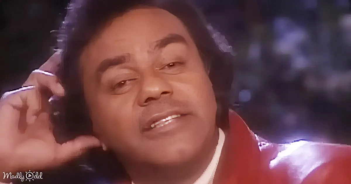 A person wearing a red jacket and holding a phone to their ear, with a blurred background.