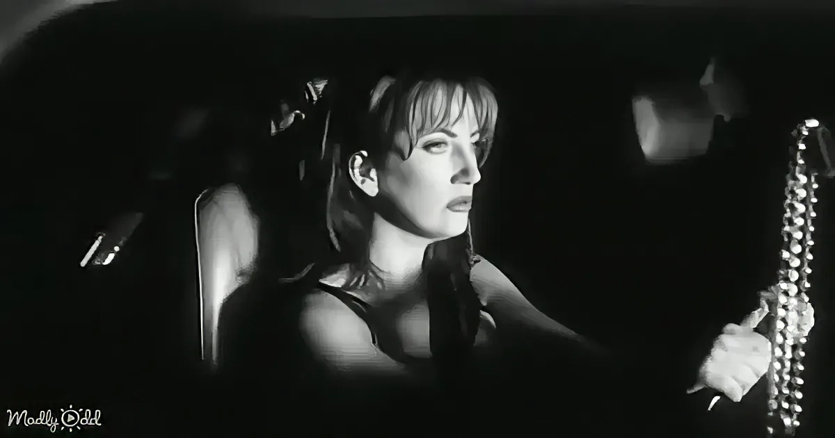 A woman sits in a car, holding a saxophone, with dramatic lighting highlighting her face.