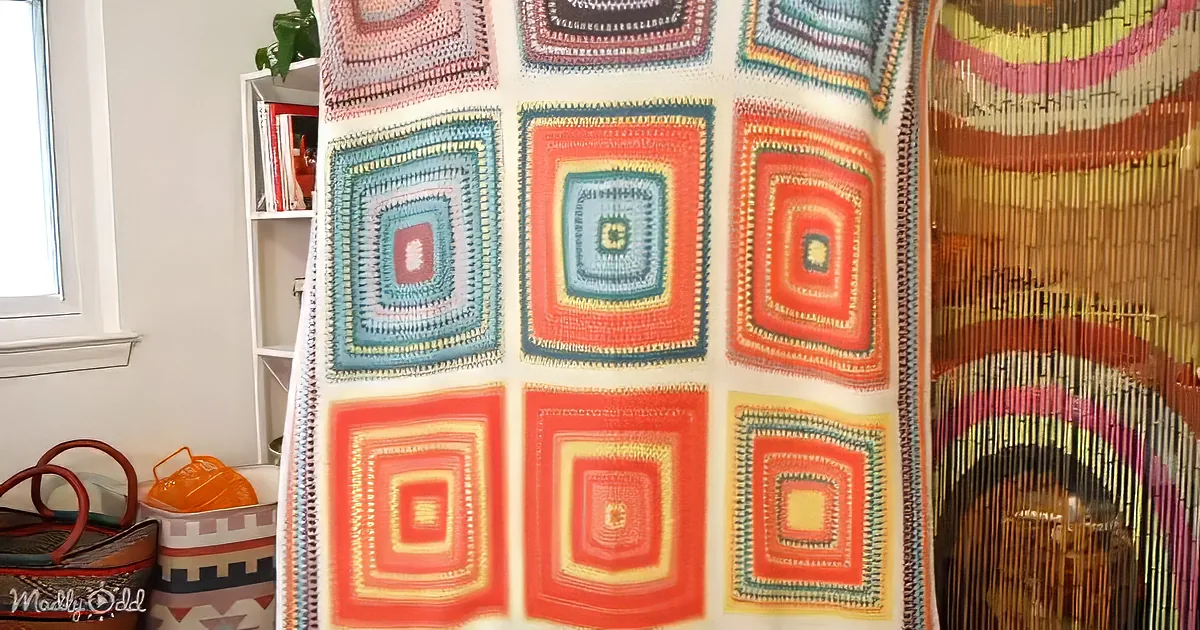 A colorful crocheted blanket with square patterns hangs in a room with a bookshelf and a beaded curtain.