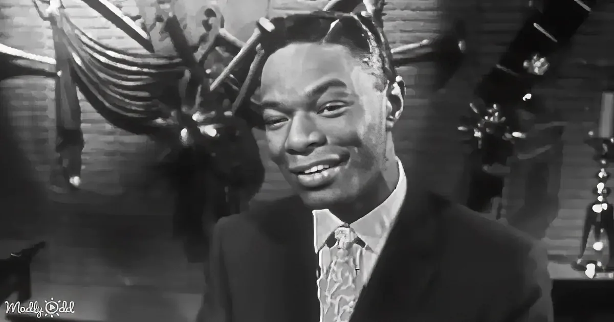 A man in a suit and tie smiles, wearing a hat with horns, in a black-and-white setting.