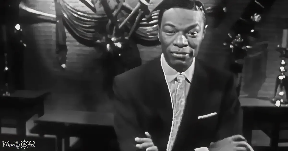 A man in a suit and tie stands in front of a band, likely performing on stage.