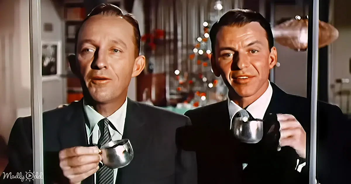 Two men in suits hold silver mugs, one with a Christmas tree in the background.
