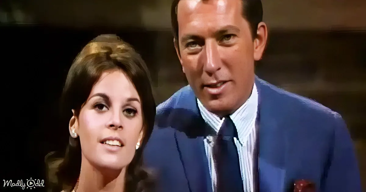 A man in a blue suit and a woman with dark hair are smiling and looking at the camera.