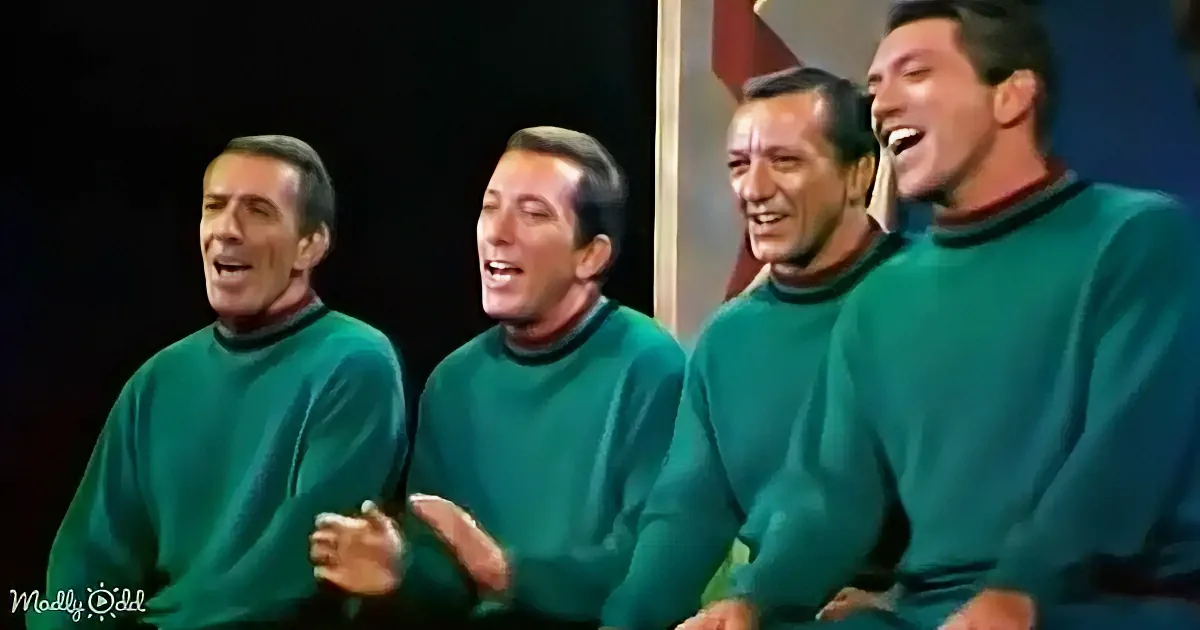 Four men in matching green sweaters are singing and smiling, creating a harmonious and joyful scene.