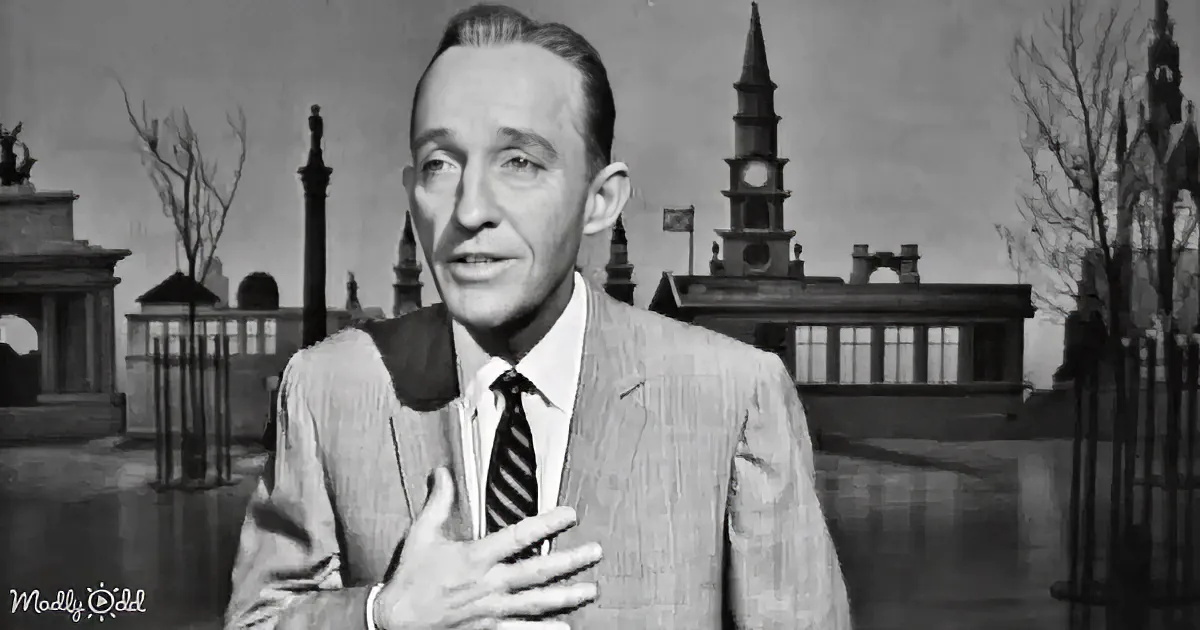 A man in a suit gestures with his hand, standing in front of a cityscape backdrop.