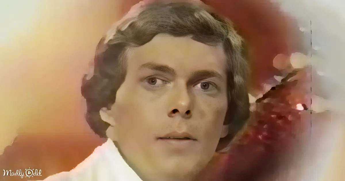 A man with short, curly brown hair and a white shirt, looking upwards.
