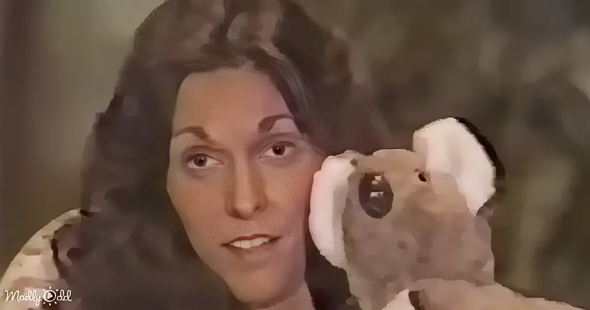 A woman with curly hair holds a stuffed animal, looking to the side with a neutral expression.