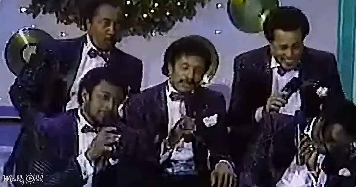 Four men in suits and bow ties are smiling and holding microphones, possibly at a formal event.