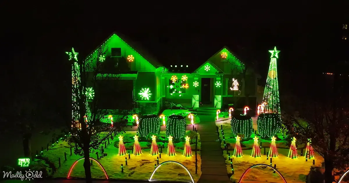 A house adorned with festive green and red lights, snowflakes, and Christmas trees, creating a magical holiday scene.