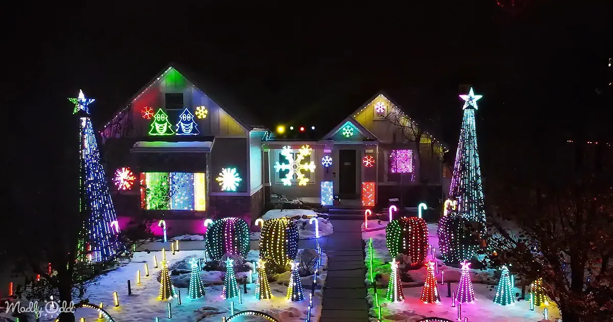 A house adorned with vibrant Christmas lights and decorations, including trees, candy canes, and snowflakes, creating a...