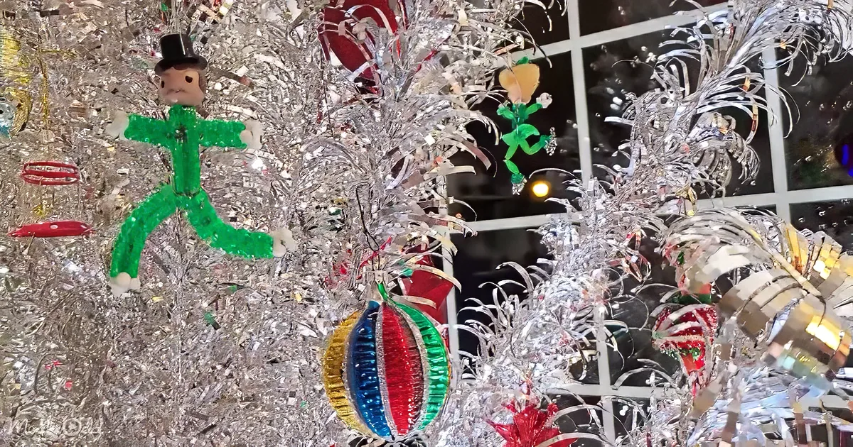 A festive Christmas tree adorned with silver tinsel, ornaments, and a green dancing figurine.