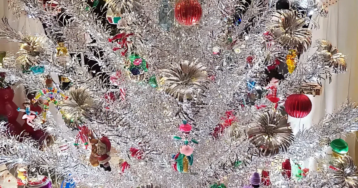A silver Christmas tree adorned with colorful ornaments, tinsel, and festive decorations.