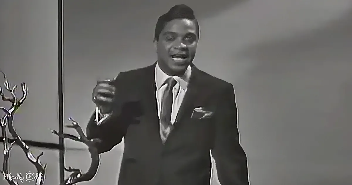 A man in a suit and tie is gesturing with his hands while speaking.