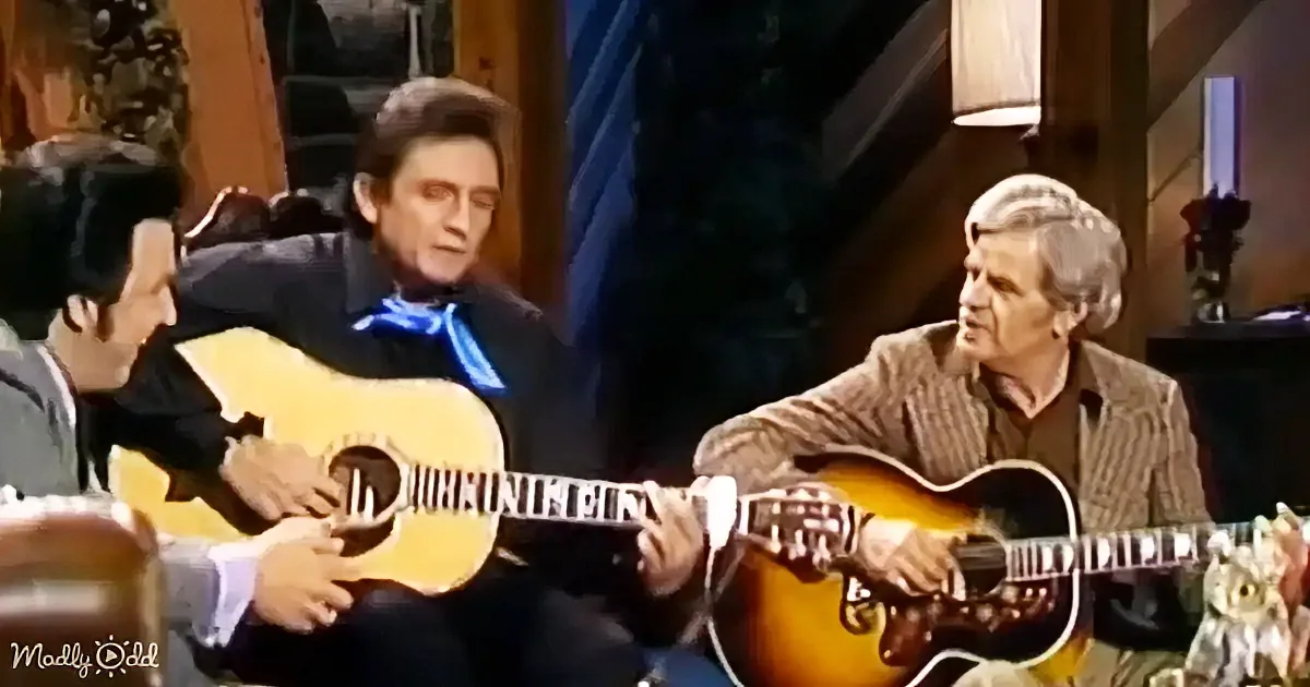 Johnny Cash plays guitar on a talk show set with two other musicians.