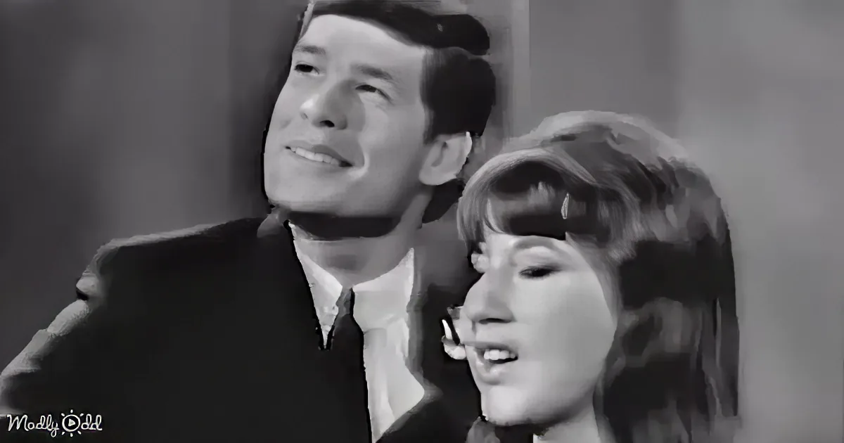 A man and woman are singing together, both looking upwards with expressions of emotion.