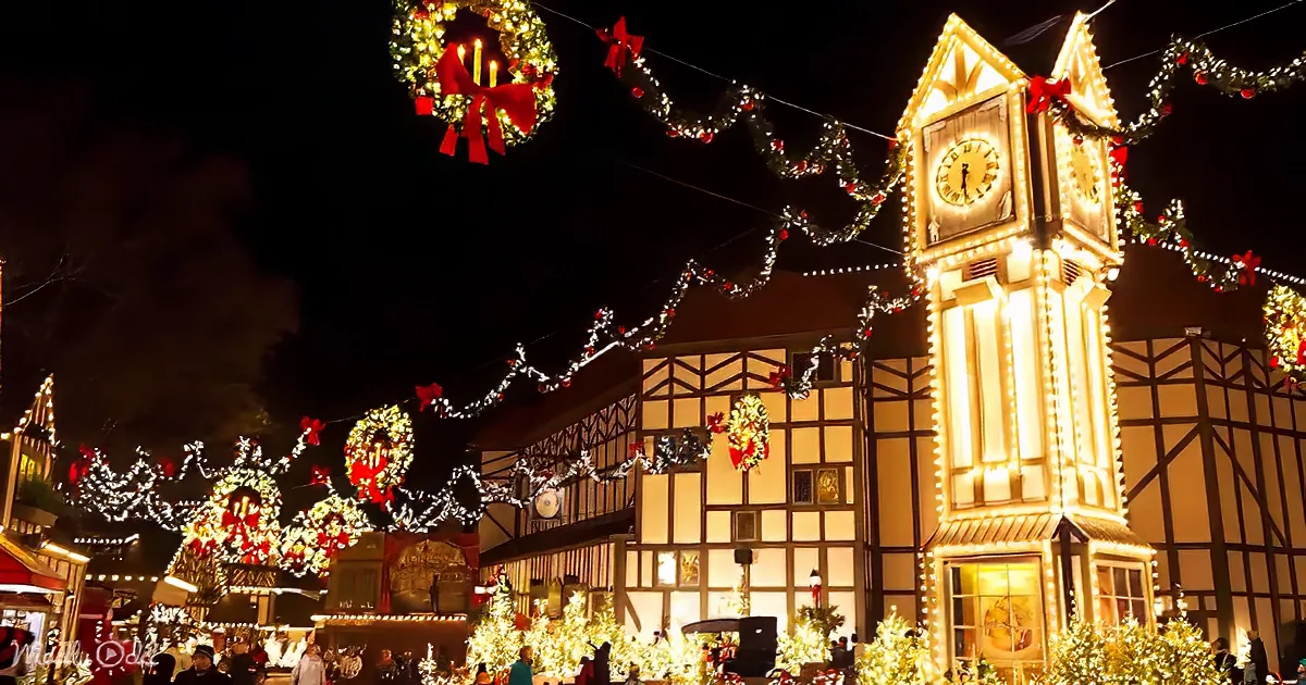 A festive night scene with illuminated clock tower and Christmas decorations adorning a building.
